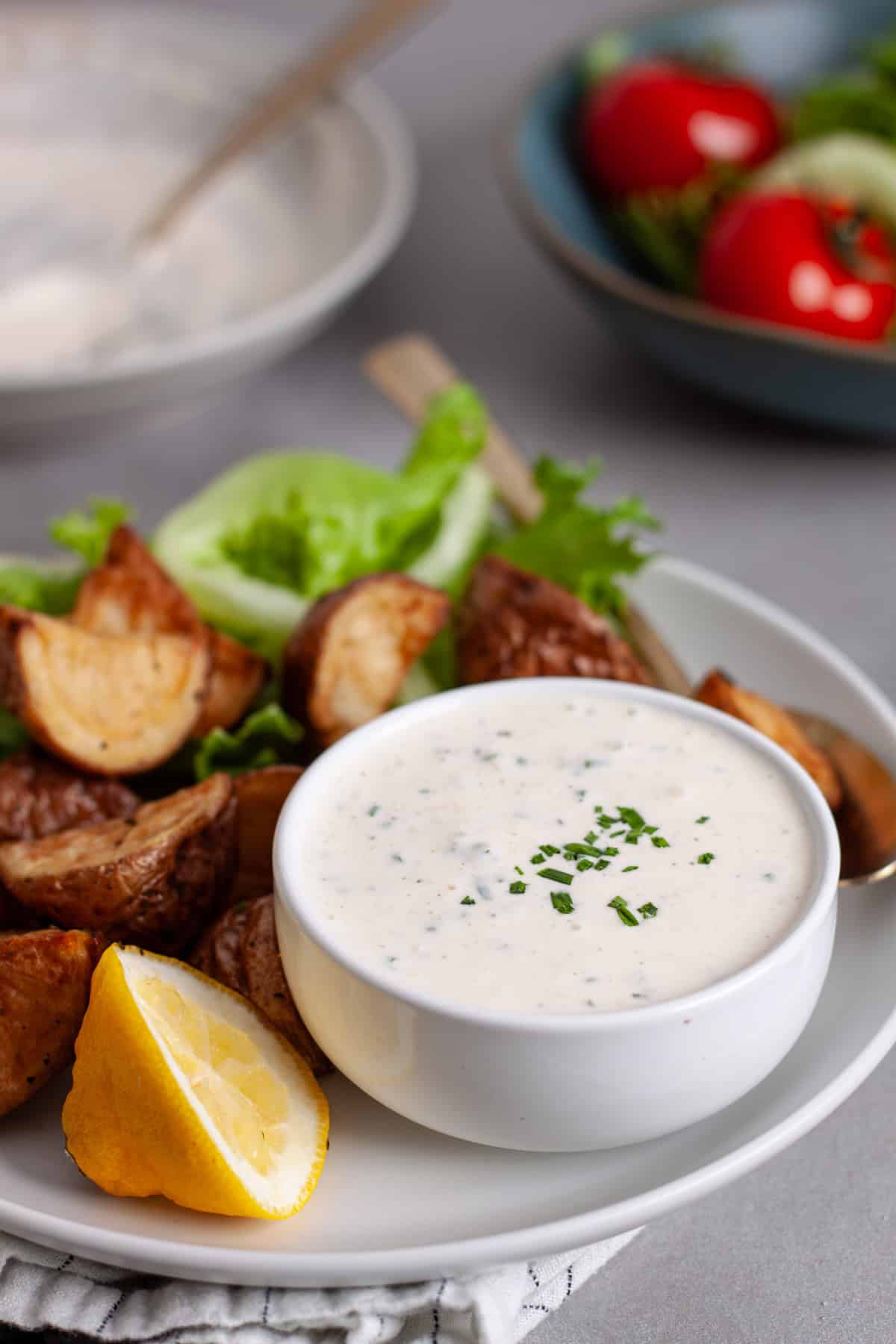 A closeup of horseradish aioli in a small bowl on a platter of crispy roasted potatoes.