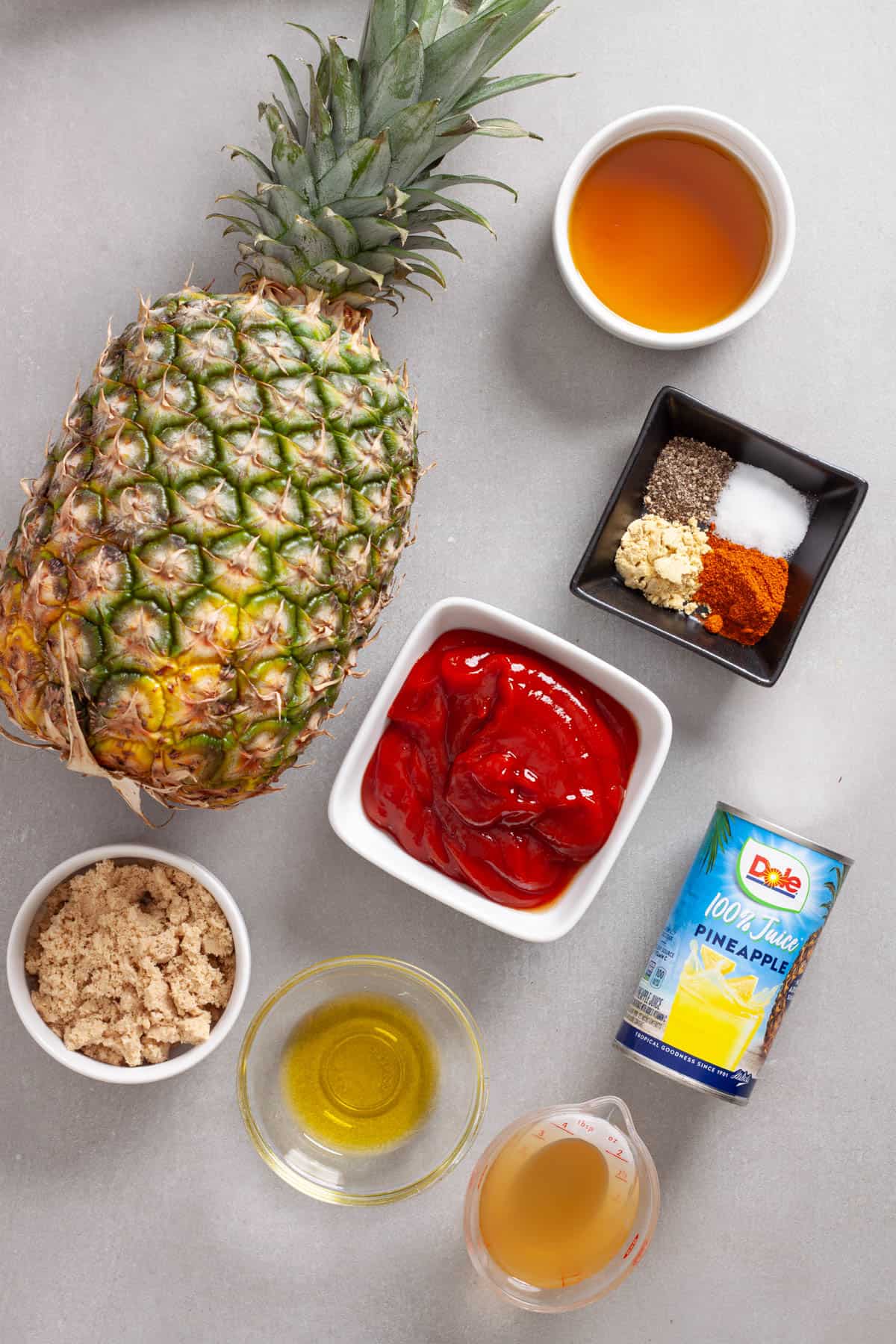 Ingredients for homemade tangy pineapple bbq sauce on a gray table.