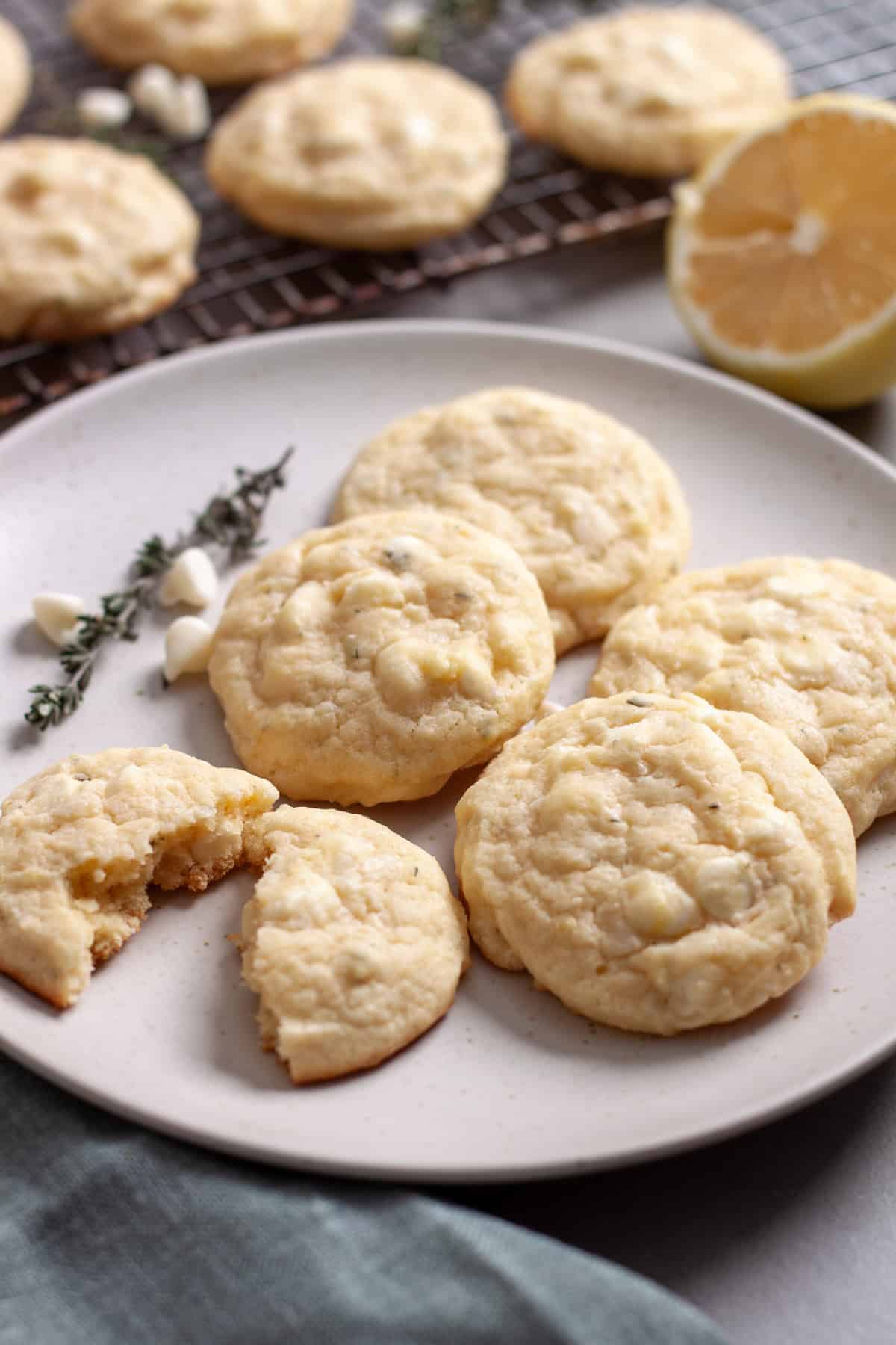 A plate of lemon white chocolate and thyme cookies with more in the background.