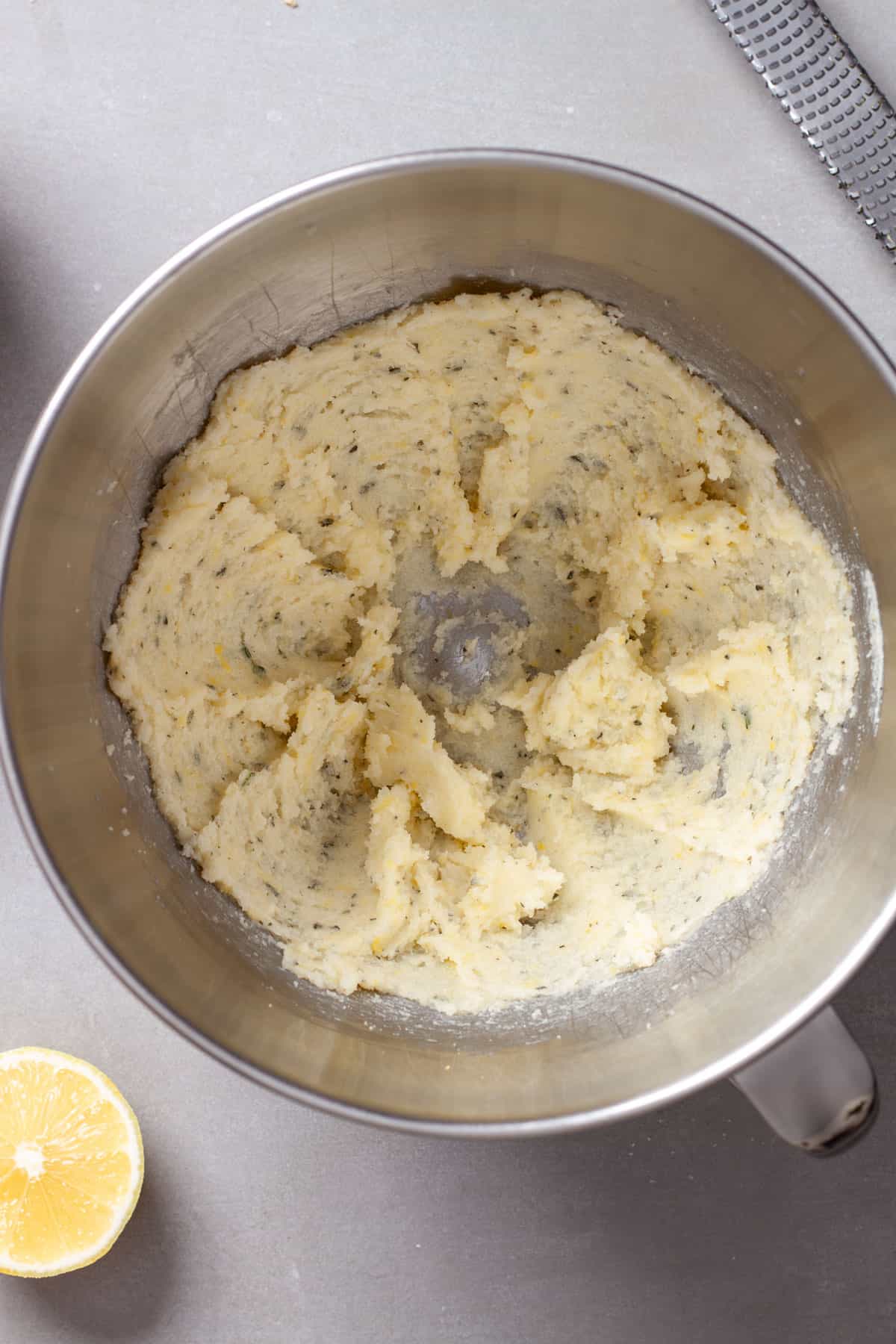 A metal bowl with butter creamed together with sugar, lemon zest and fresh thyme.