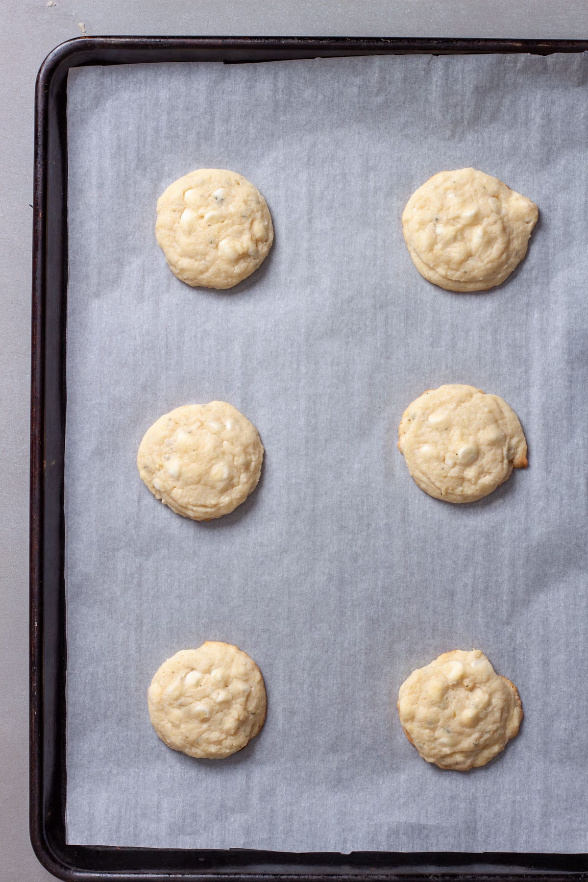 Lemon white chocolate chip cookies hot out of the oven on a parchment lined baking sheet.