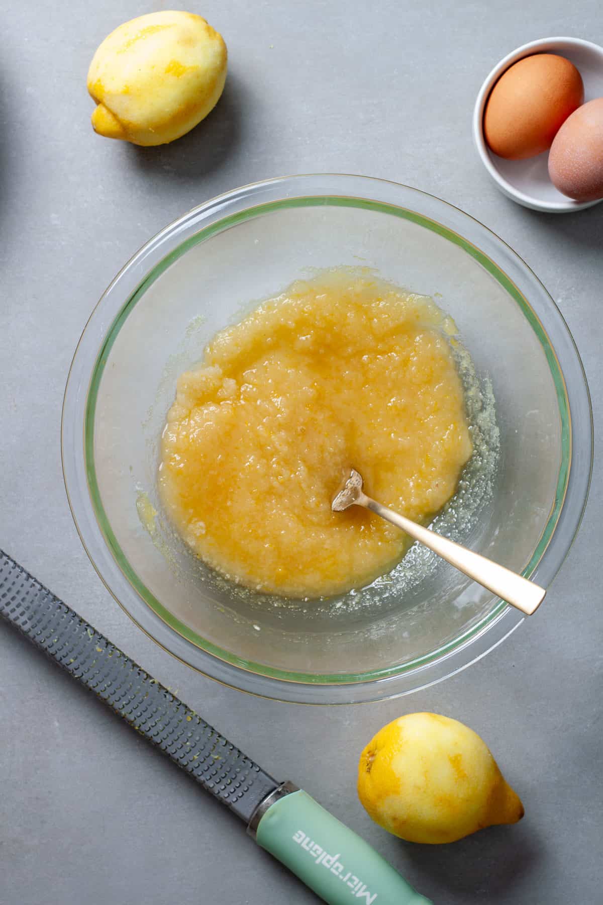 Wet ingredients for lemon and vanilla blondies in a glass bowl on a gray table.