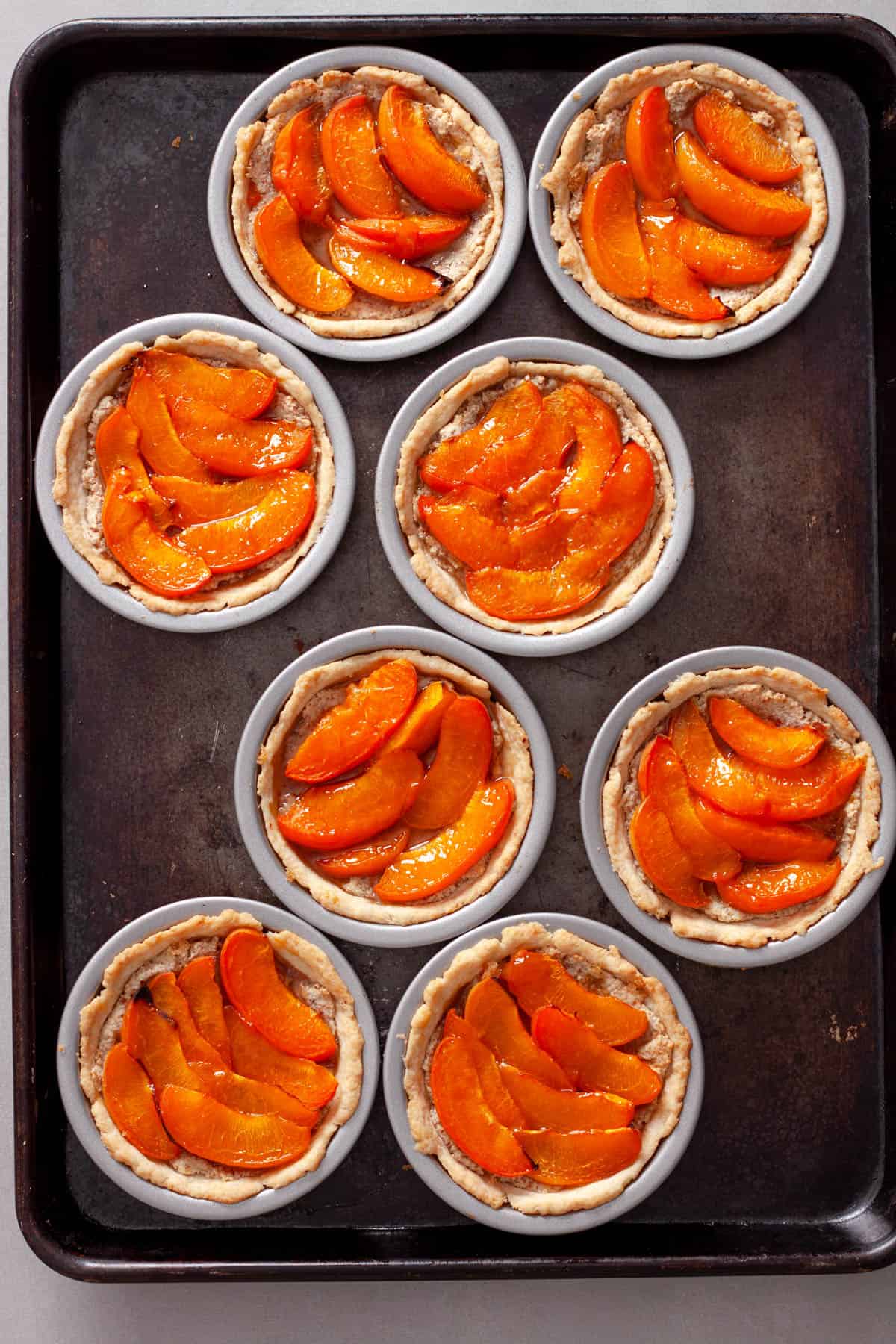 A baking sheet of cooked apricot tarts fresh out of the oven.
