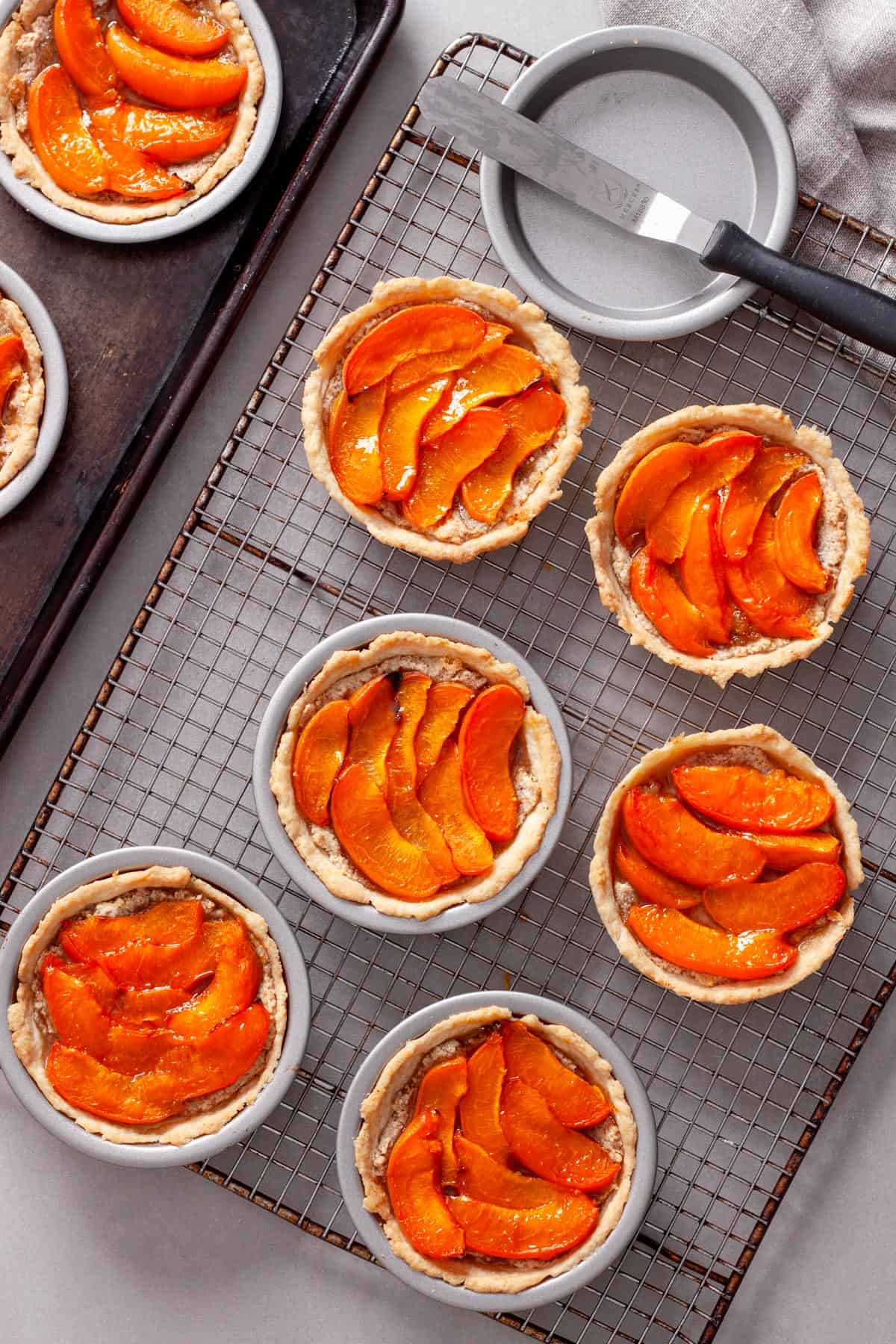 Mini apricot and almond tarts cooling on a wire rack.