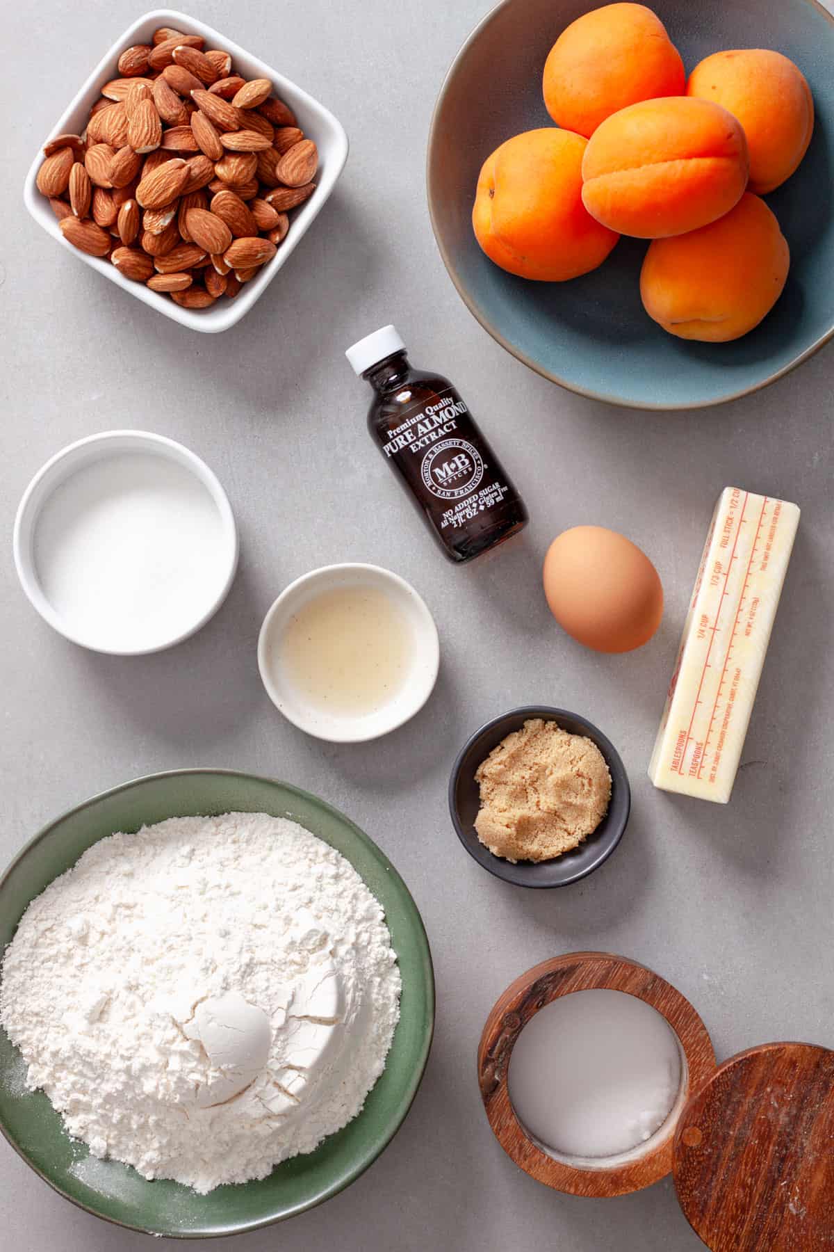 Ingredients for mini apricot and almond tarts on a gray table.