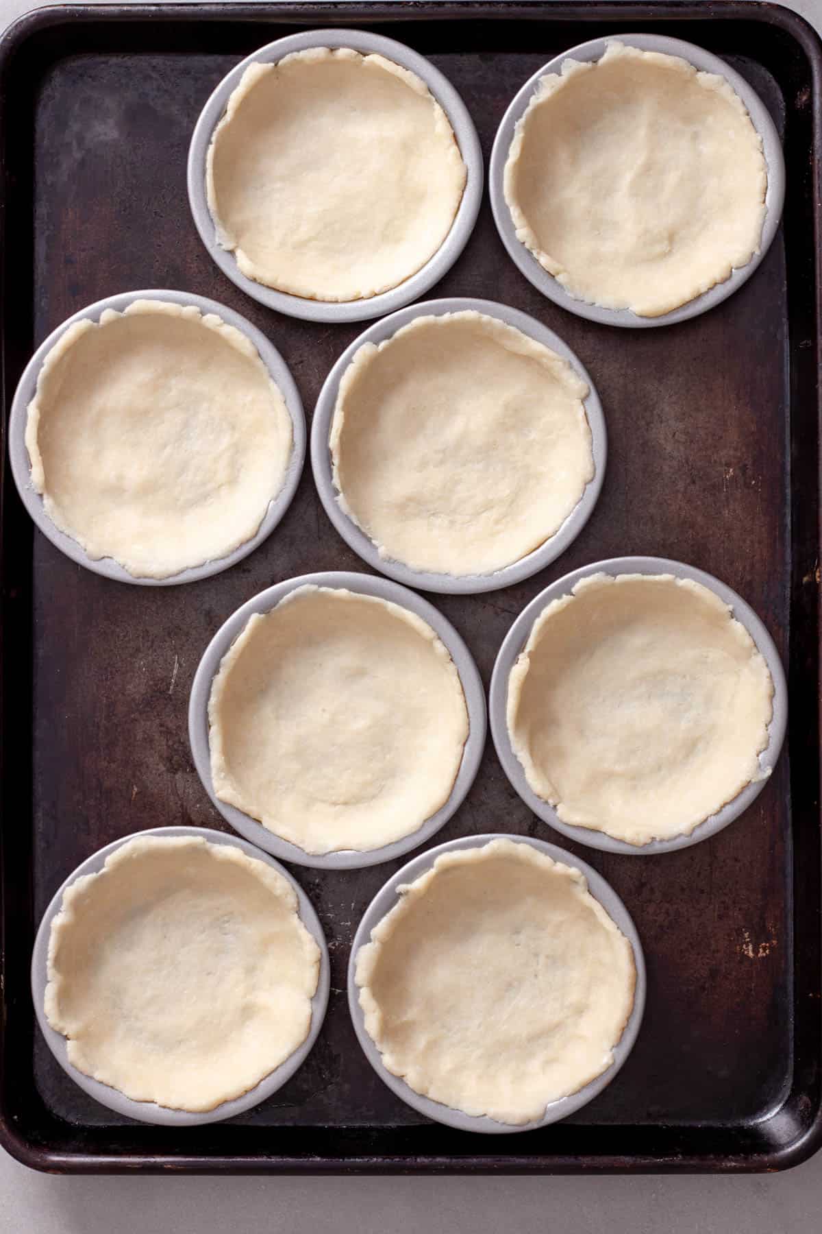 Mini tart pans with pie dough pressed into the pan.