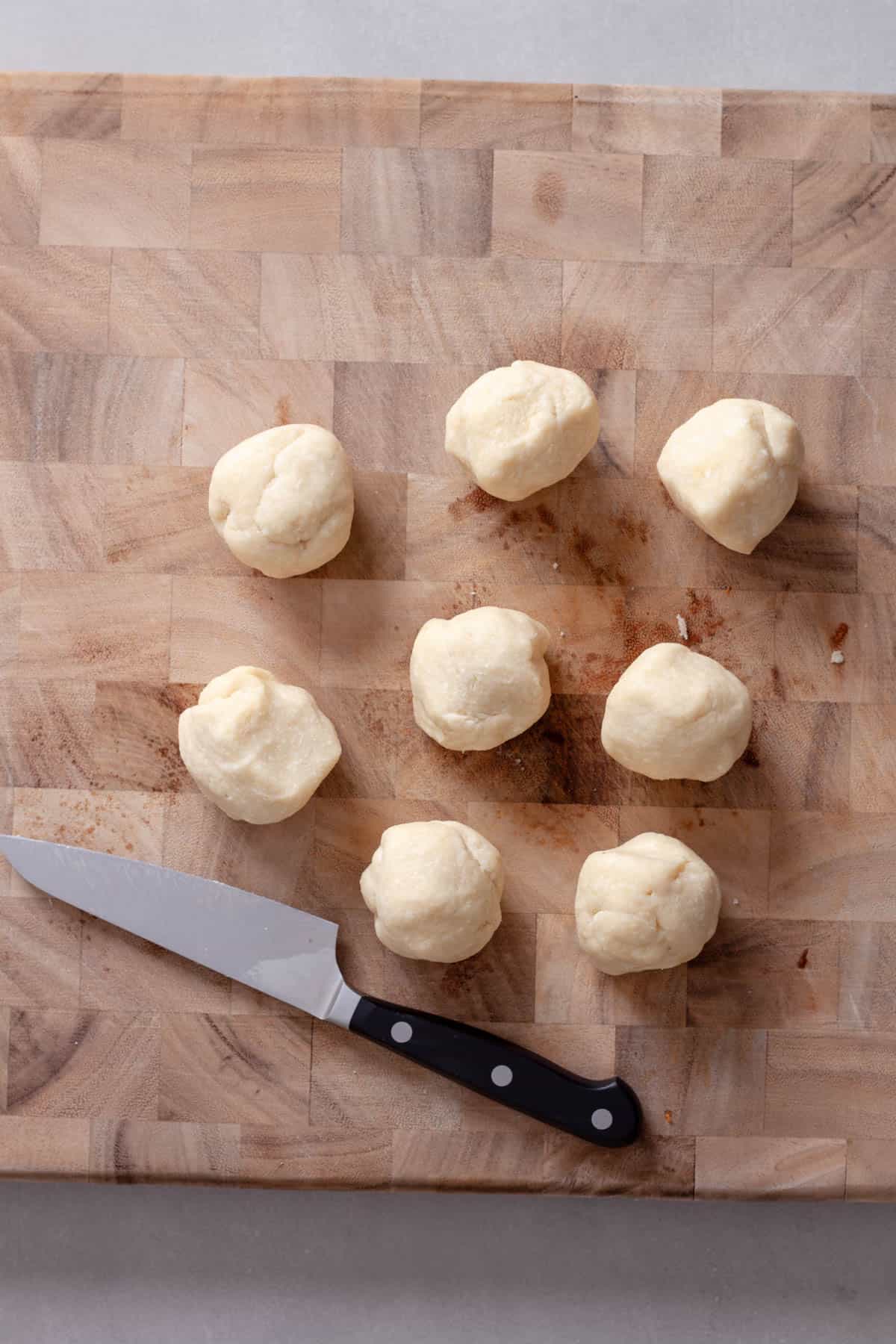 Pie dough rolled into small balls on a cutting board for apricot tarts.