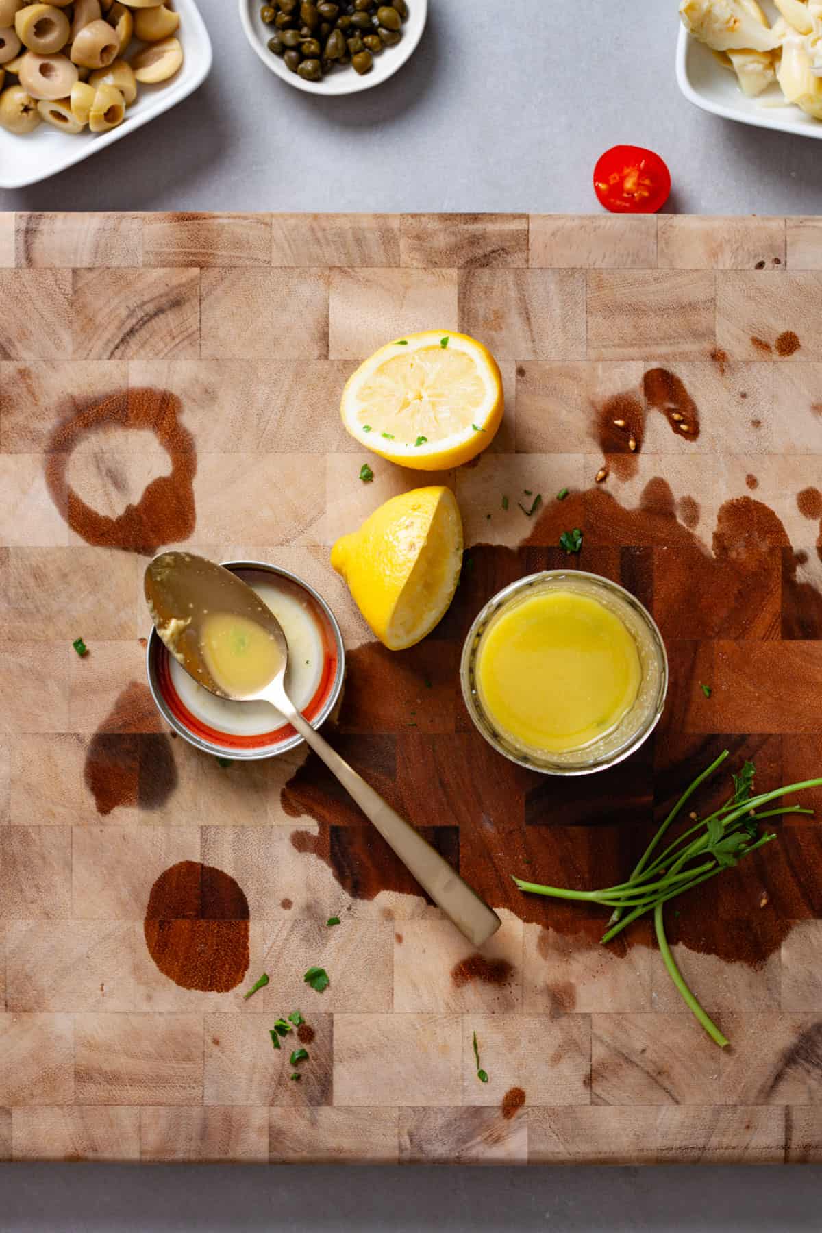 Lemon and herb vinaigrette in a mason jar on a butcherblock cutting board.