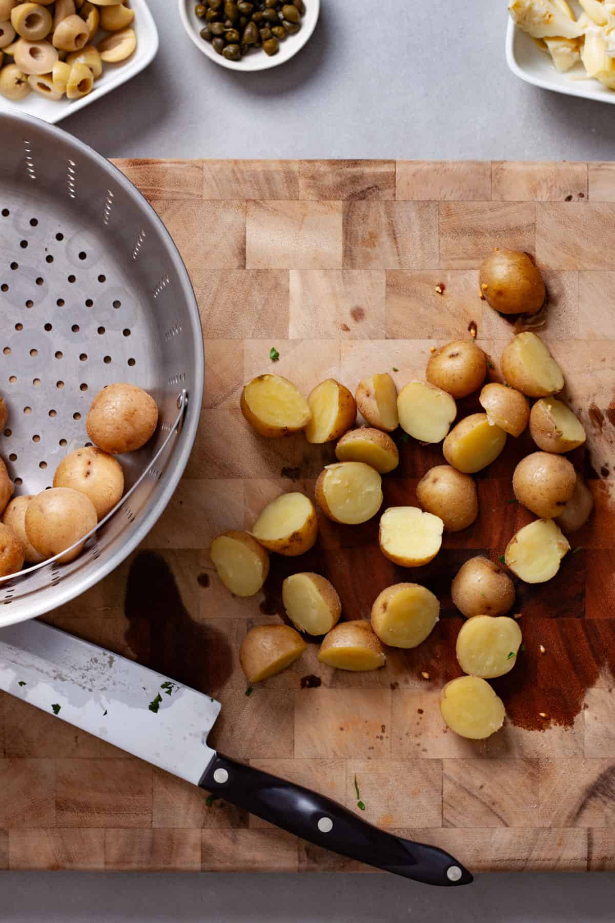 Steamed potatoes getting chopped on a cutting board.