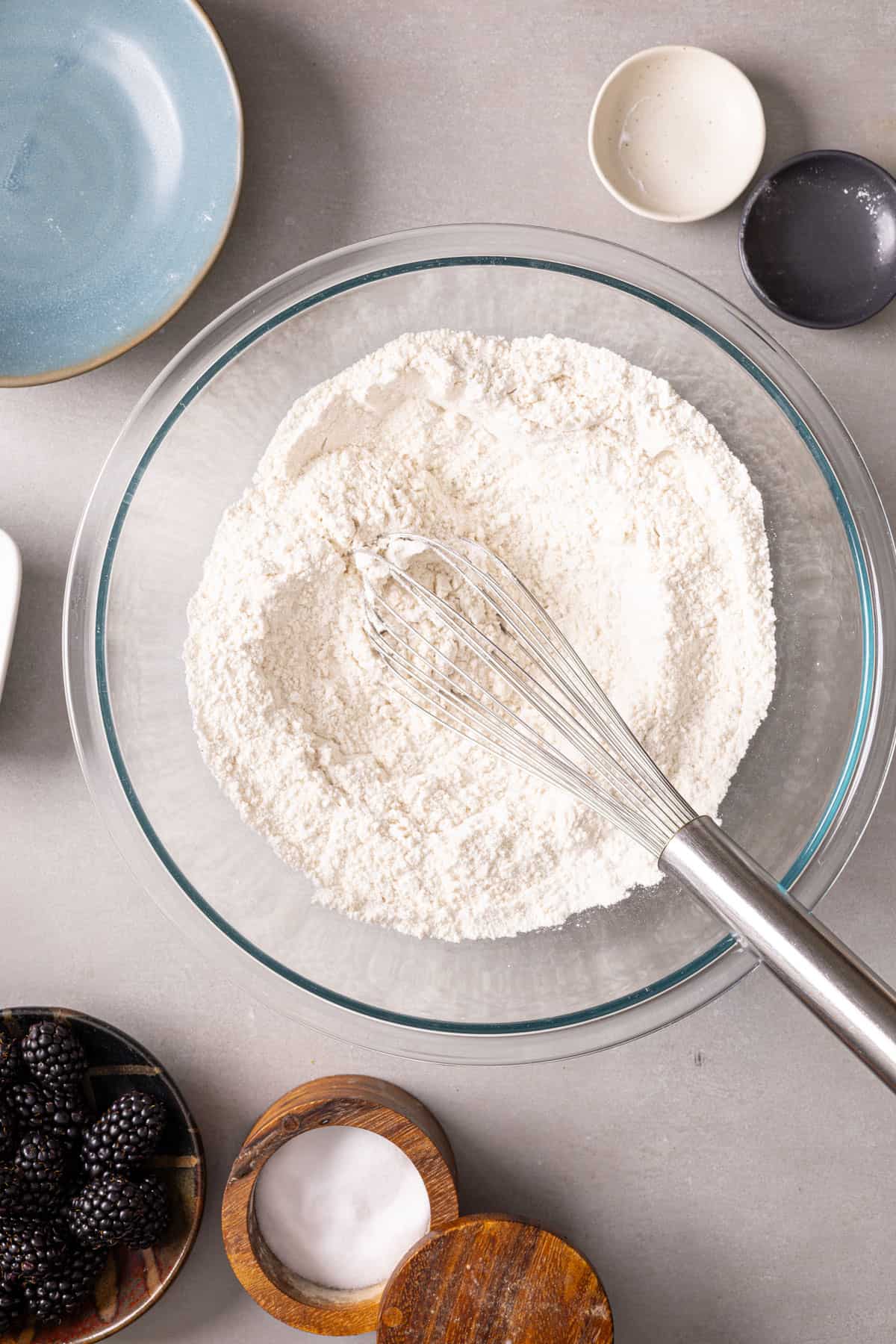 Dry ingredients for muffins whisking in a glass mixing bowl.