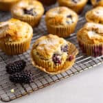 Gluten free blackberry muffins cooling on a wire rack on a gray table.