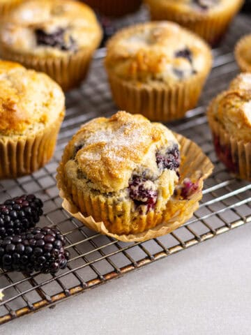Gluten free blackberry muffins cooling on a wire rack on a gray table.