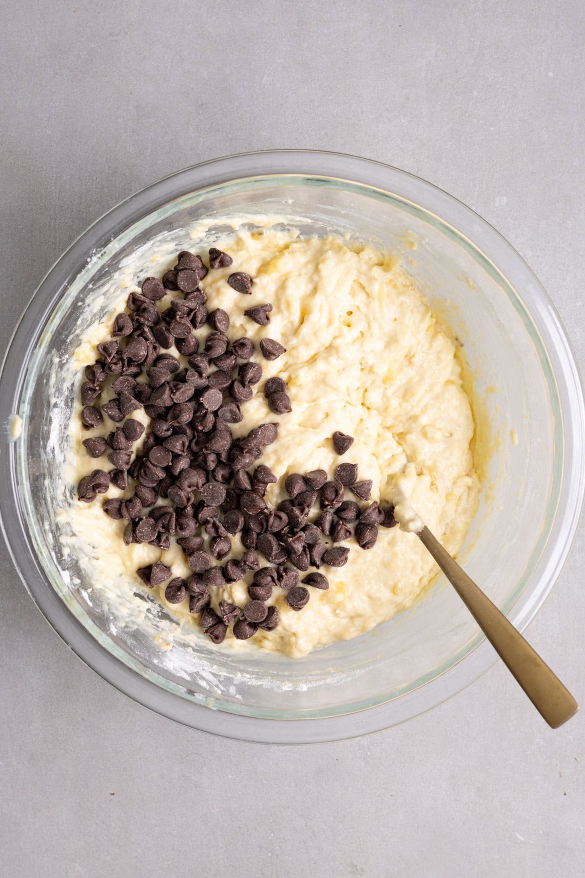 Chocolate chips getting stirred into a bowl of muffin batter.