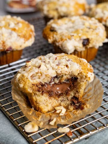 A nutella stuffed muffin on a napkin with a bite taken out and more muffins in the background.