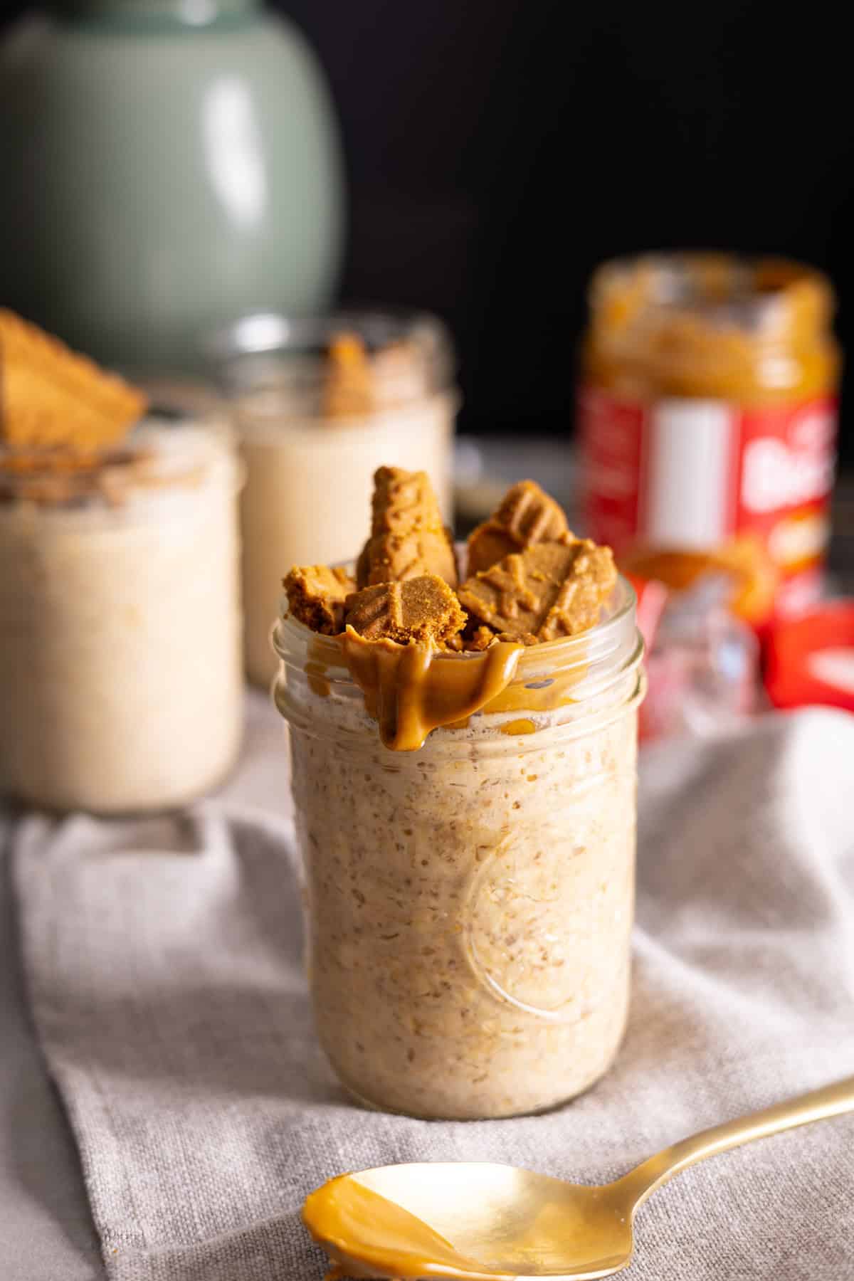 A mason jar of Biscoff overnight oats topped with cookies and cookie butter.