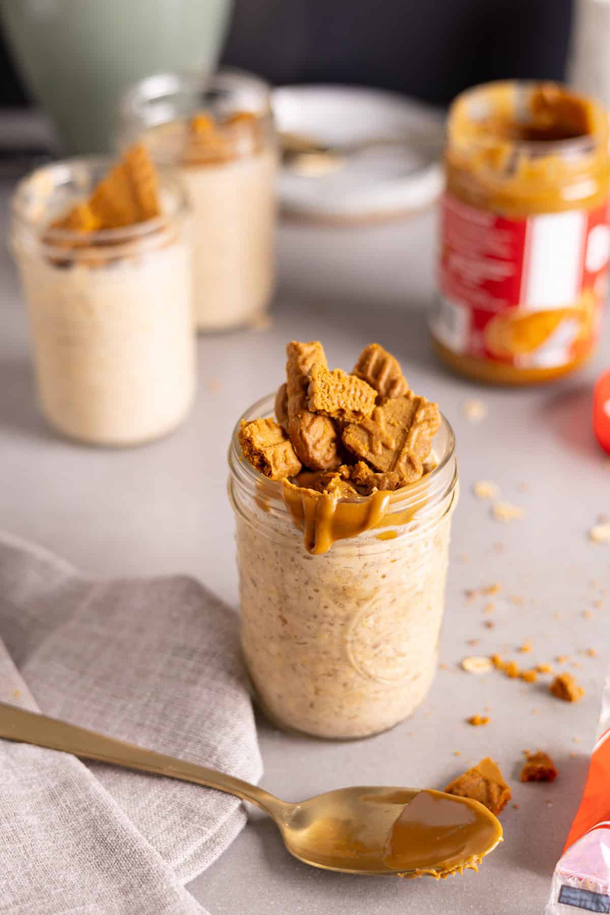 Several mason jars with biscoff overnight oats on a gray table.