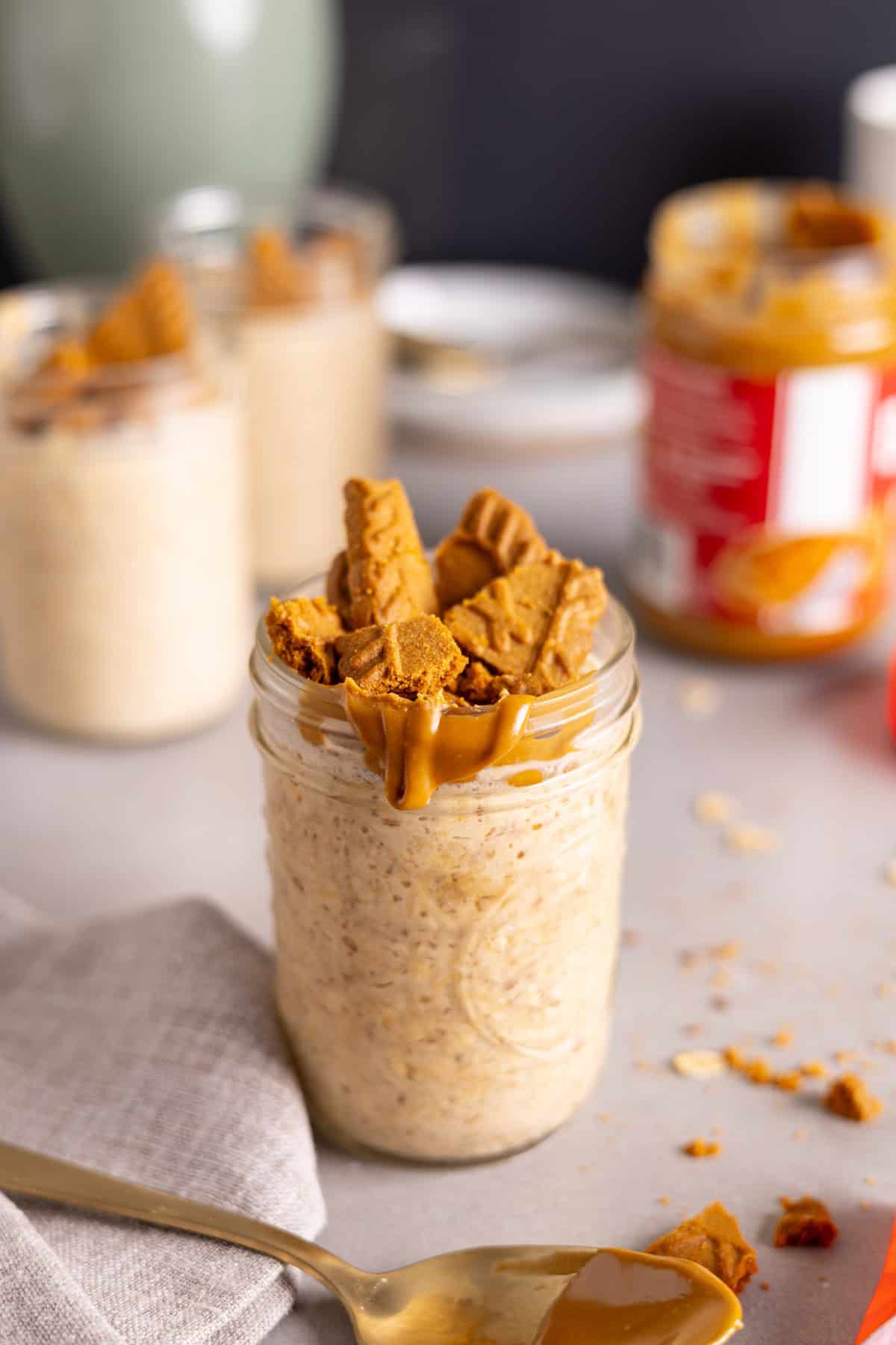 Several mason jars with biscoff overnight oats on a gray table.