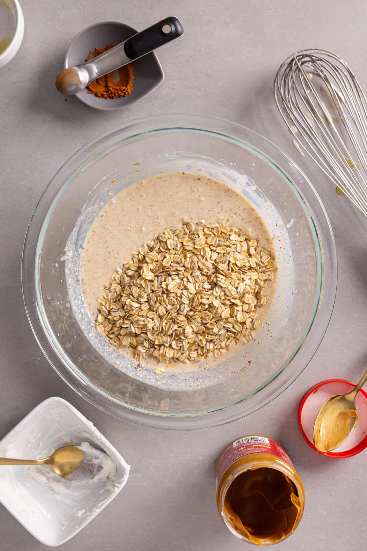 Oats added to a bowl with the wet ingredients for cookie butter overnight oats.