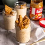 Several mason jars with biscoff overnight oats on a gray table.