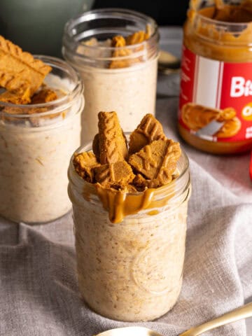 Several mason jars with biscoff overnight oats on a gray table.