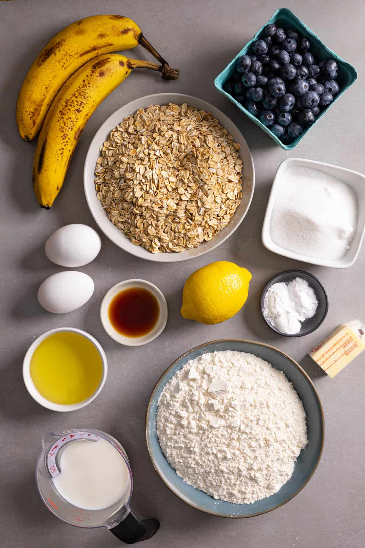 Ingredients for blueberry banana oat muffins on a gray table.