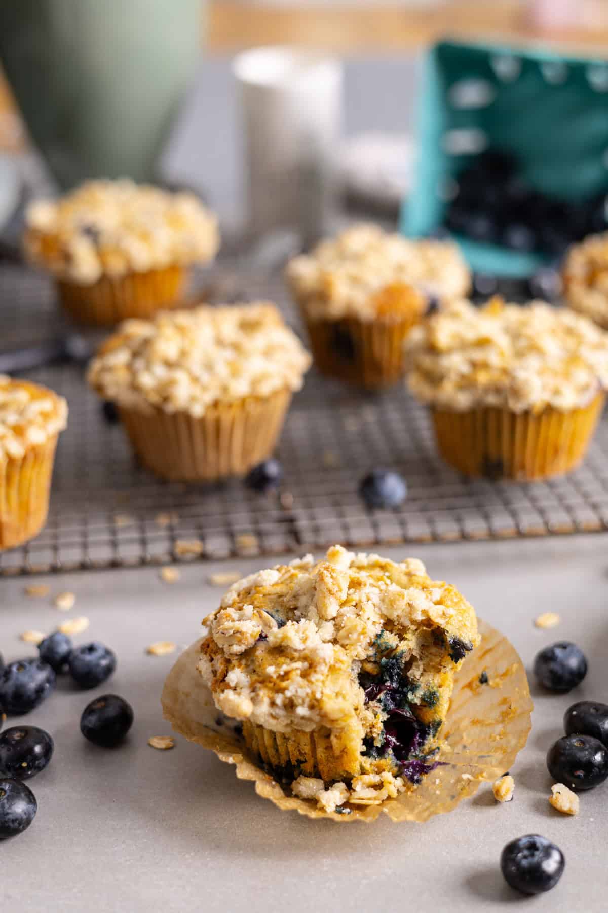 Blueberry banana oat muffins cooling on a wire rack with a  bite out of a single serving.