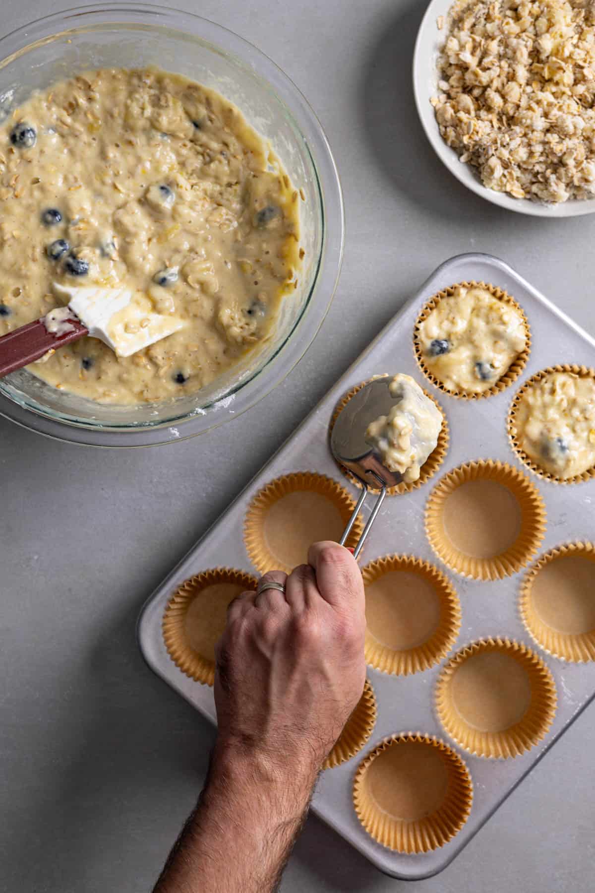 Muffin batter getting poured into a muffin tin.