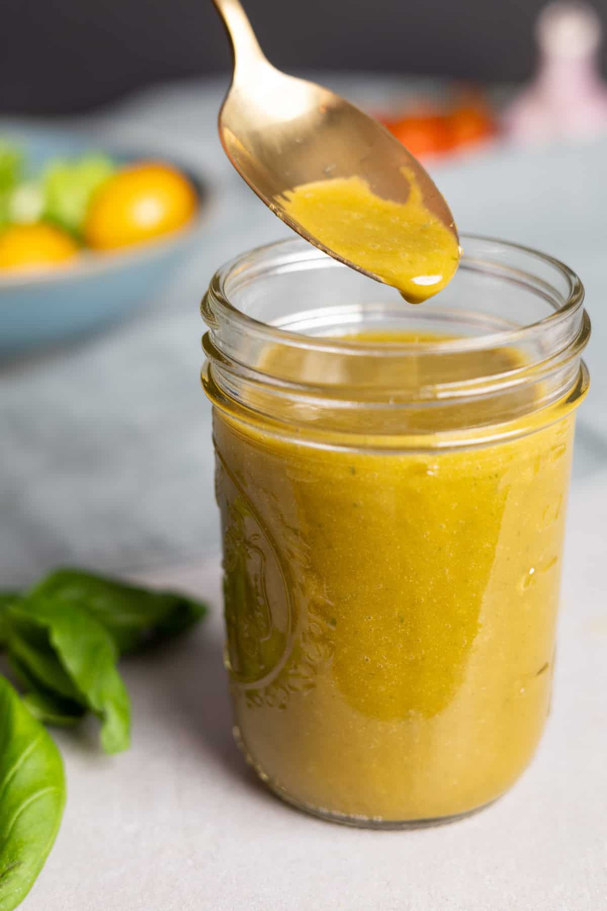 Basil balsamic vinaigrette in a small mason jar with a spoon taking out a bit.
