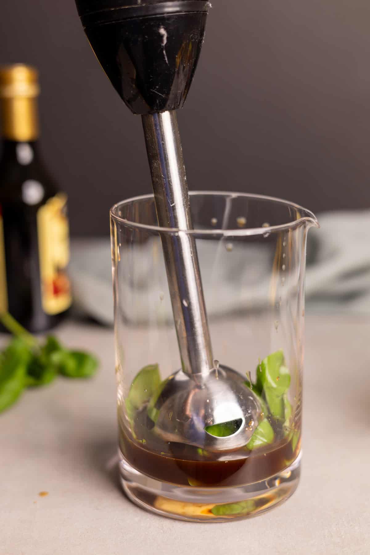 Ingredients for basil balsamic vinaigrette in a glass jar with an immersion blender.
