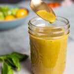 Basil balsamic vinaigrette in a small mason jar with a spoon taking out a bit.