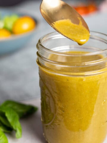 Basil balsamic vinaigrette in a small mason jar with a spoon taking out a bit.