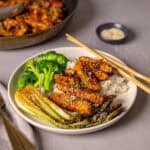 A serving of honey ginger chicken with rice, broccoli and bok choy on a small plate.