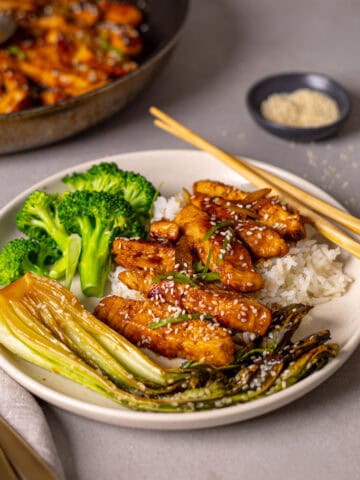 A serving of honey ginger chicken with rice, broccoli and bok choy on a small plate.