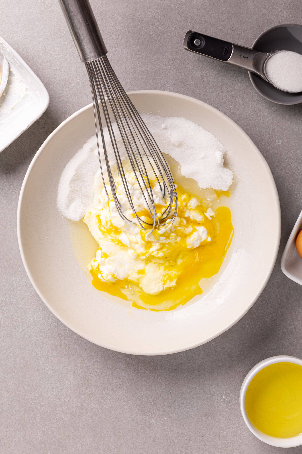 Eggs and sugar in a white bowl getting whisked.
