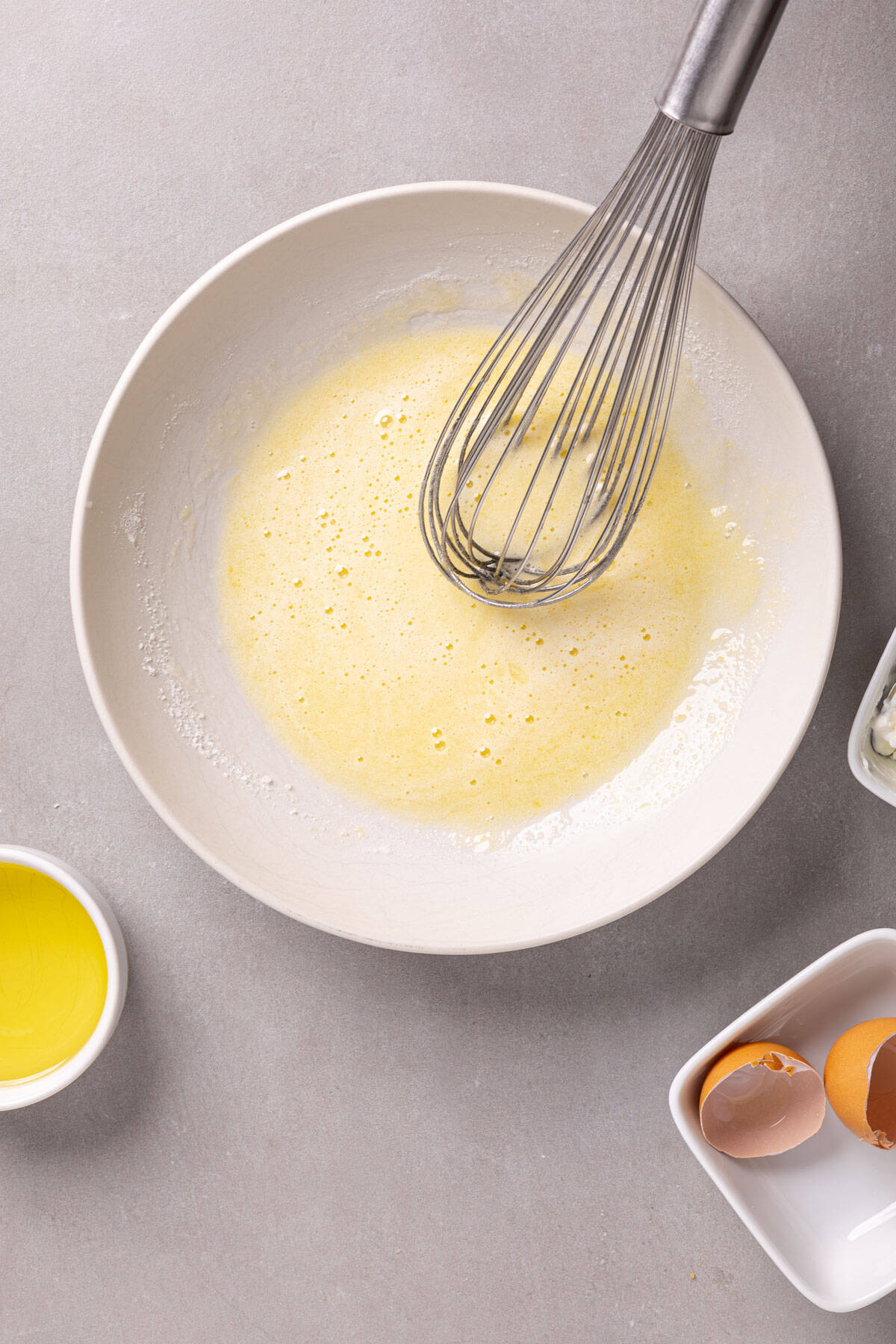 Wet mixture for a yogurt cake getting mixed in a white bowl.