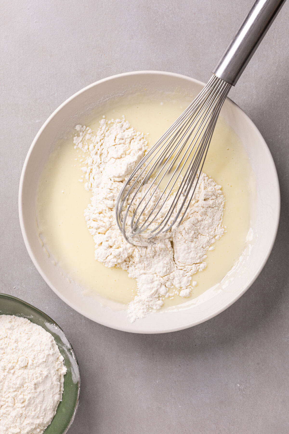 Flour getting whisked into wet ingredients for a yogurt cake.