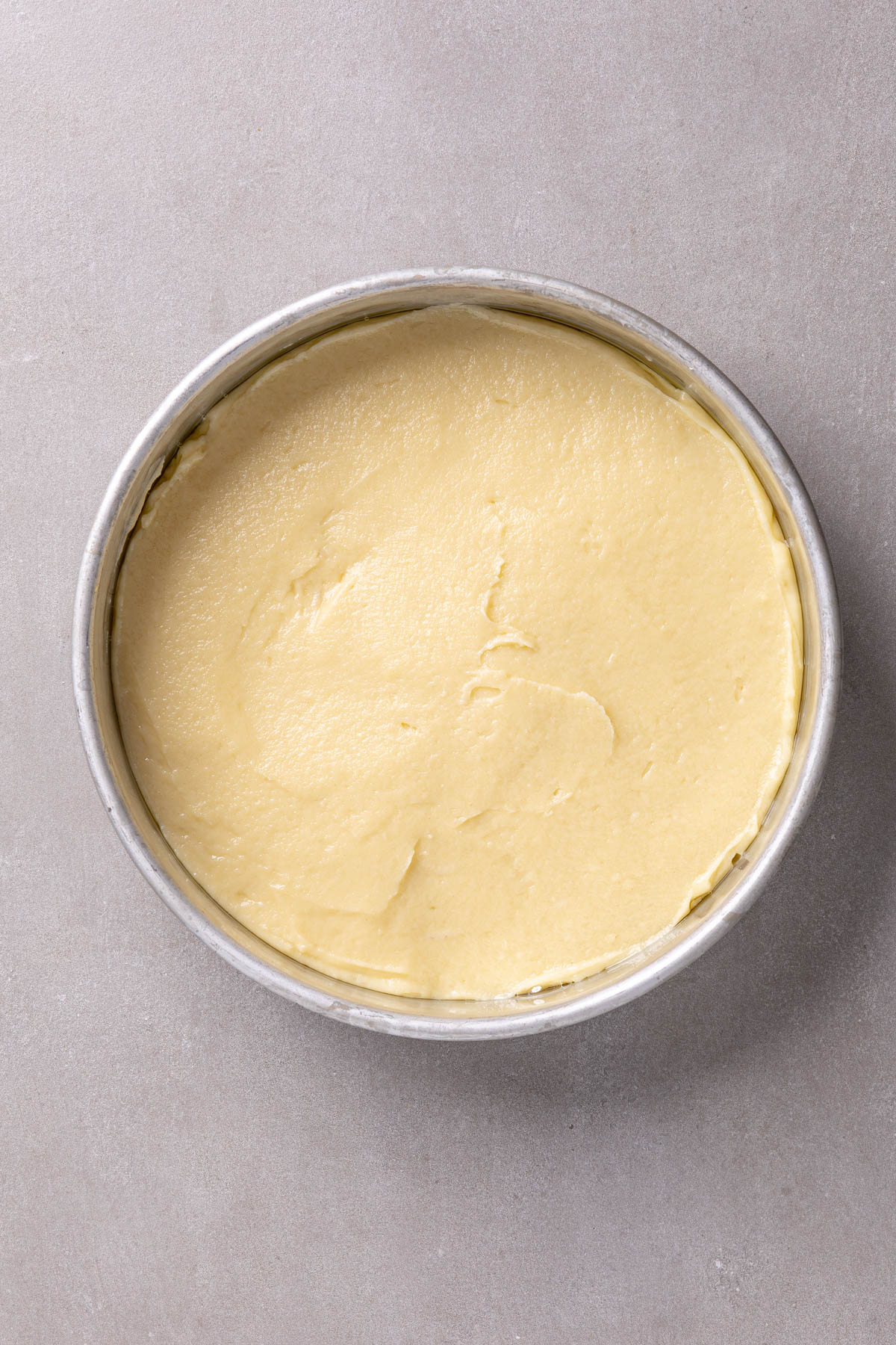 Yogurt cake batter in a round cake pan spread smooth.