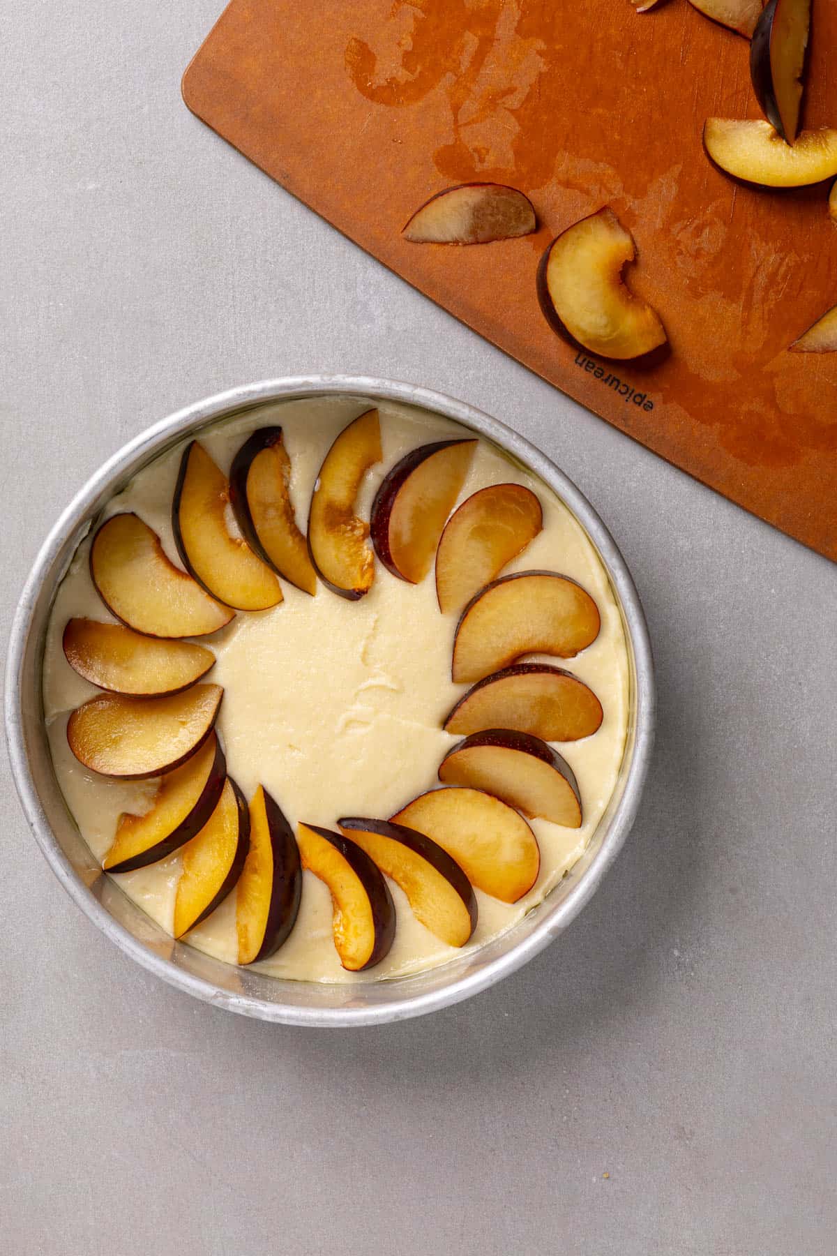 Sliced plums placed on top of a yogurt cake.