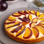 A close up of a yogurt plum cake on a gray plate.