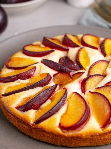 A close up of a yogurt plum cake on a gray plate.