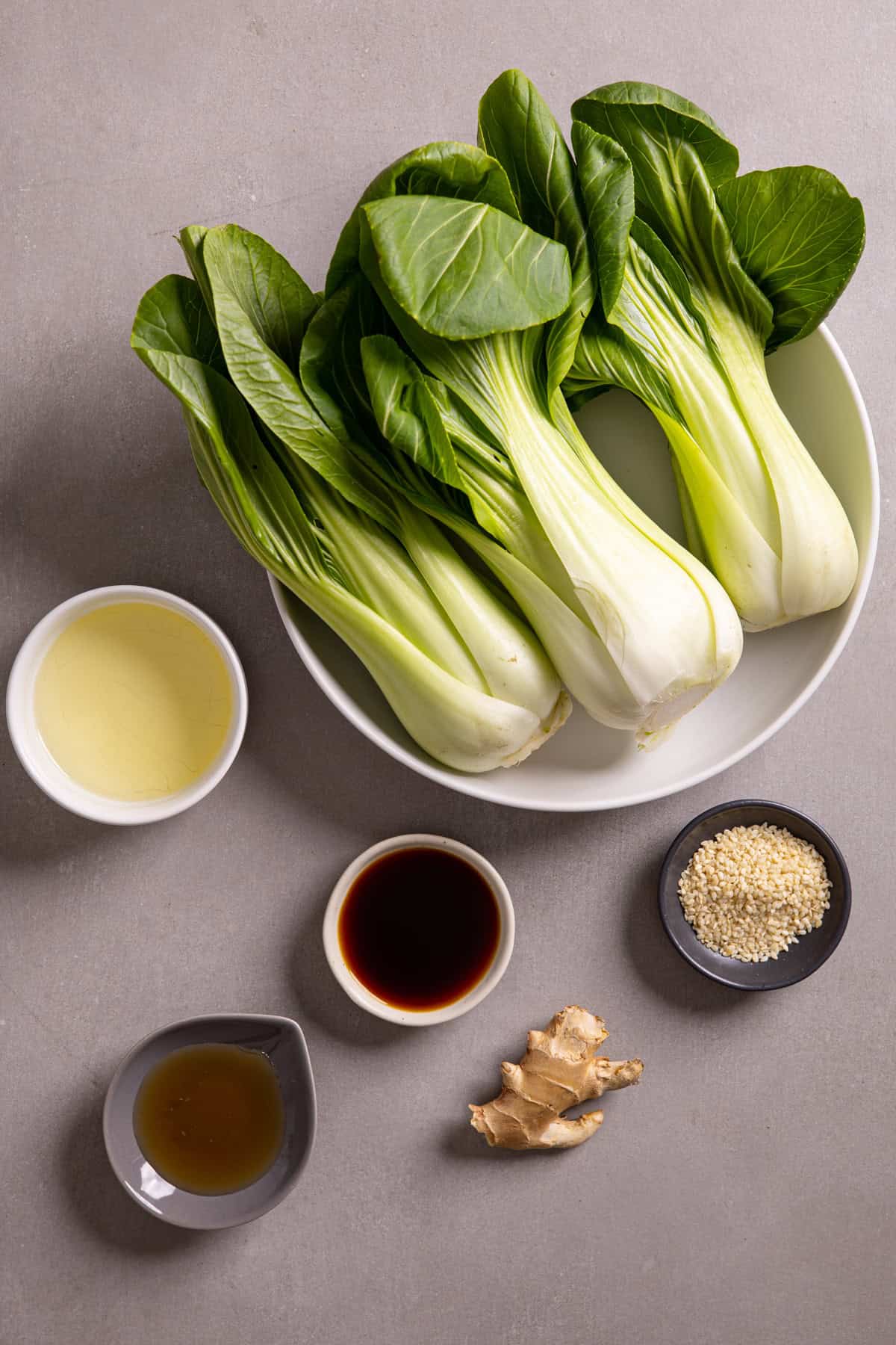 Ingredients for roasted baby bok choy on a gray table.