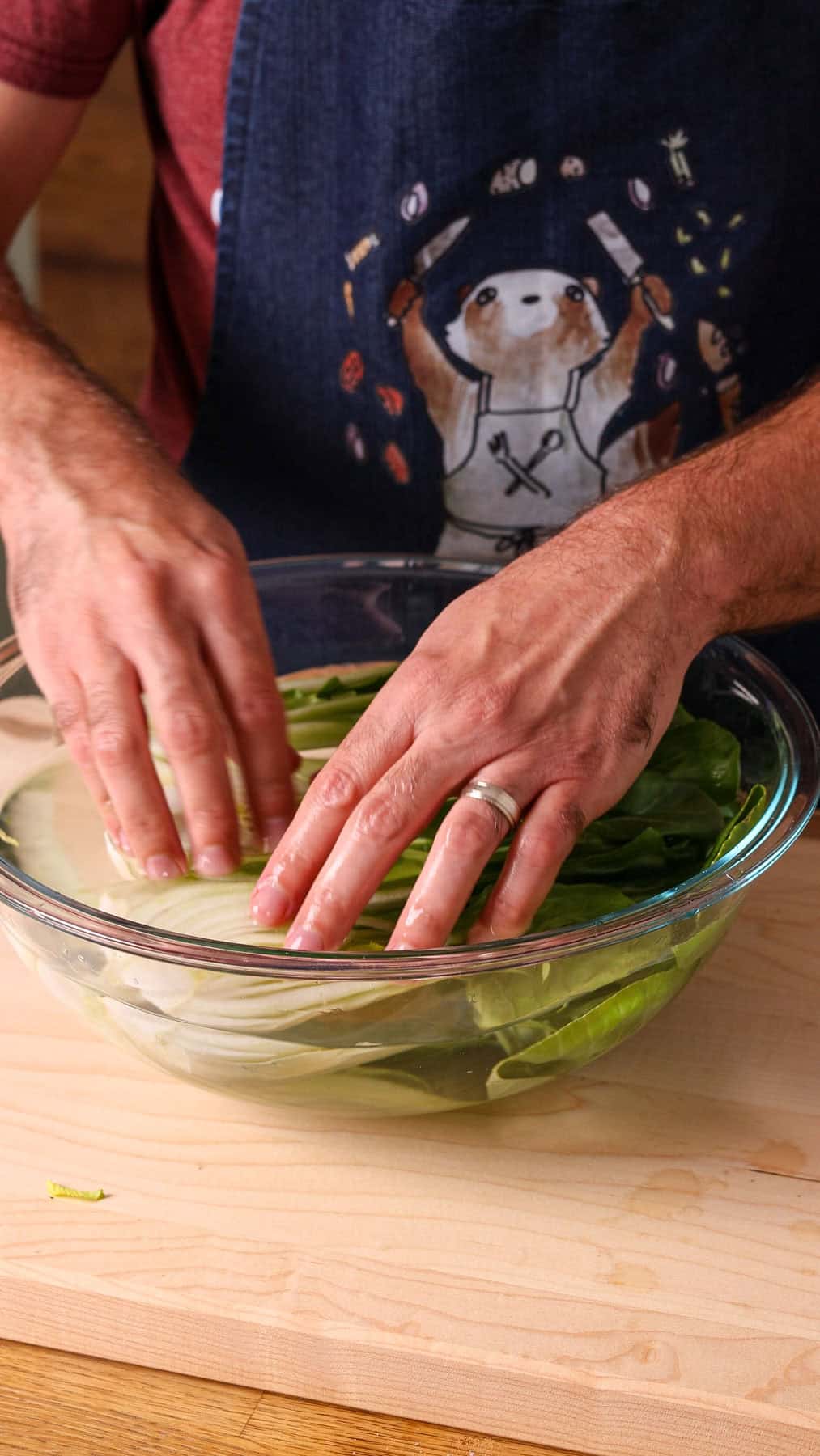 Baby bok choy halves getting washed in a bowl of water.