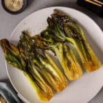 A platter of roasted bok choy lightly browned and garnished with sesame seeds.