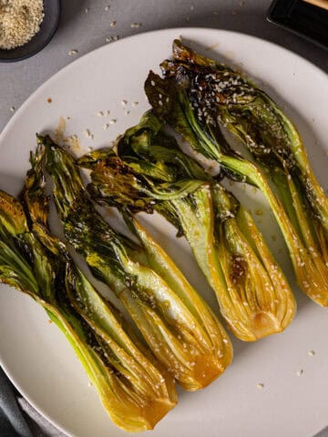 A platter of roasted bok choy lightly browned and garnished with sesame seeds.