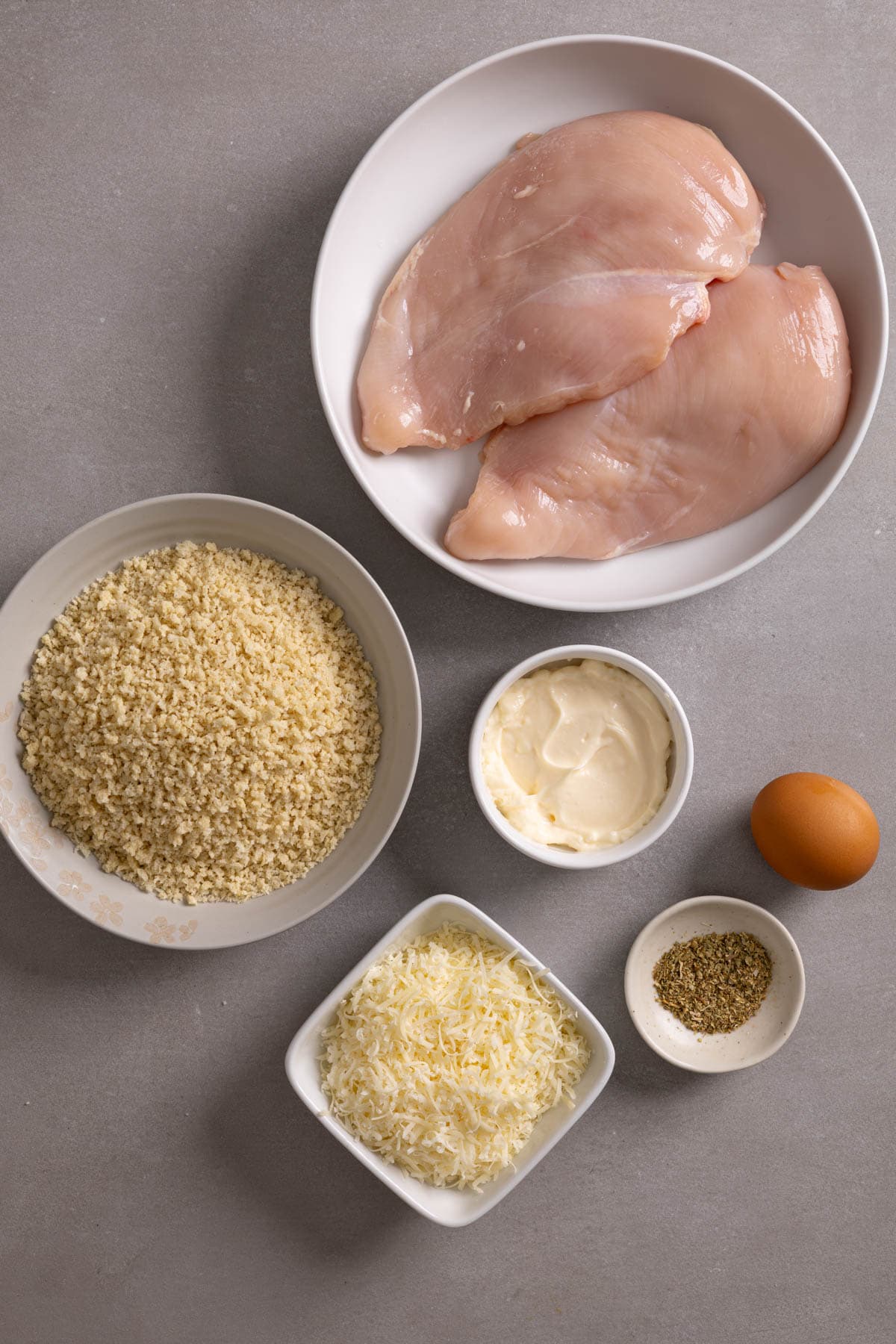 Ingredients for parmesan crusted air fryer chicken on a gray table.