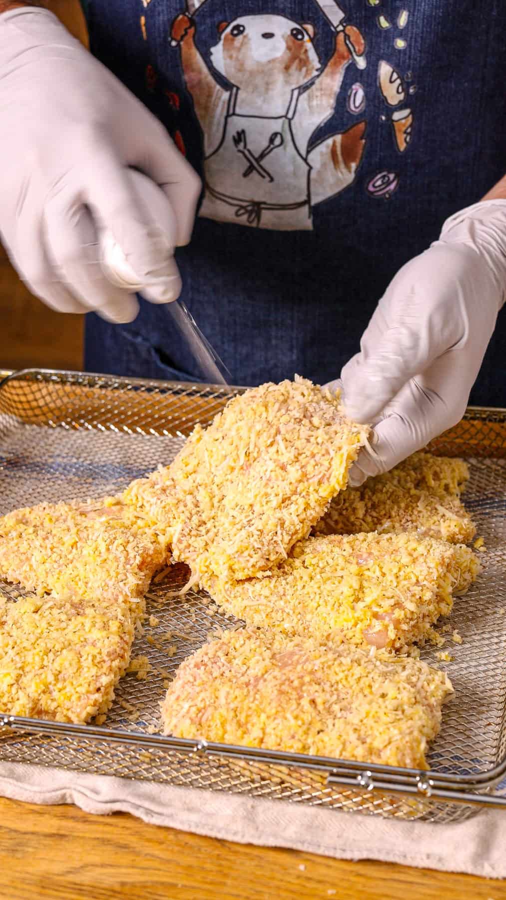 Panko crusted chicken getting spayed with cooking spray.