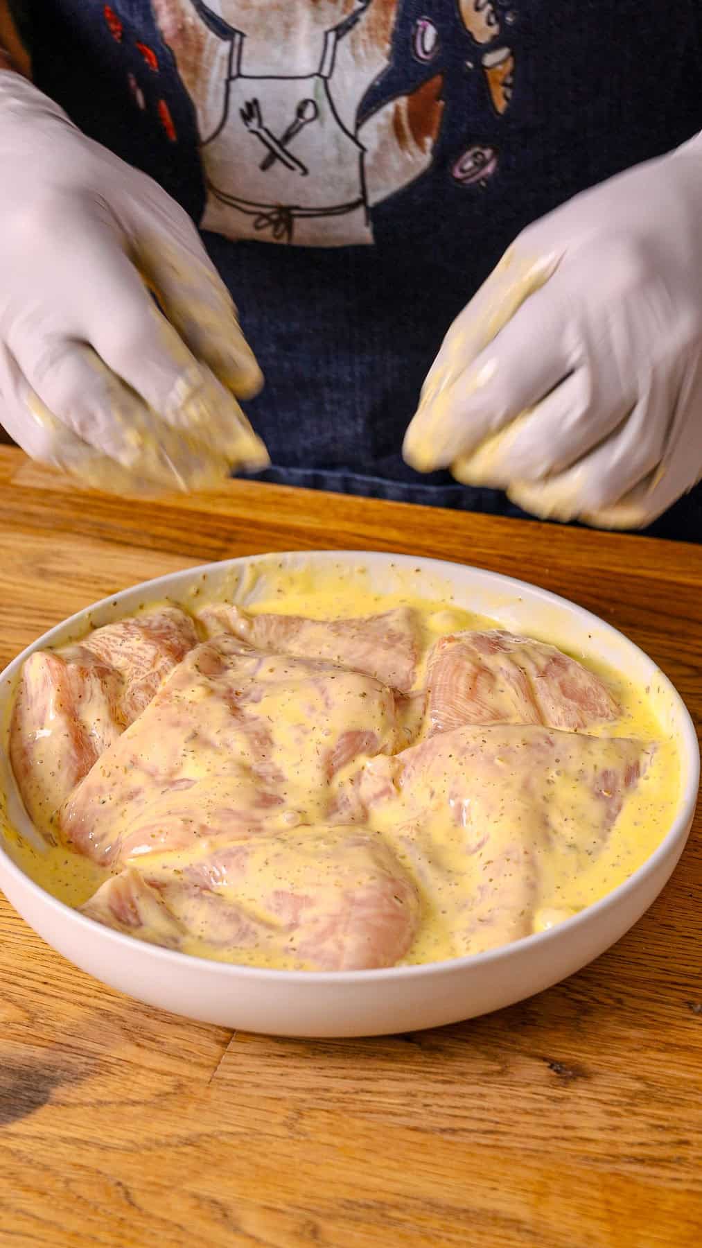 Trimmed chicken breasts in a marinade of mayo, italian seasoning, and egg.