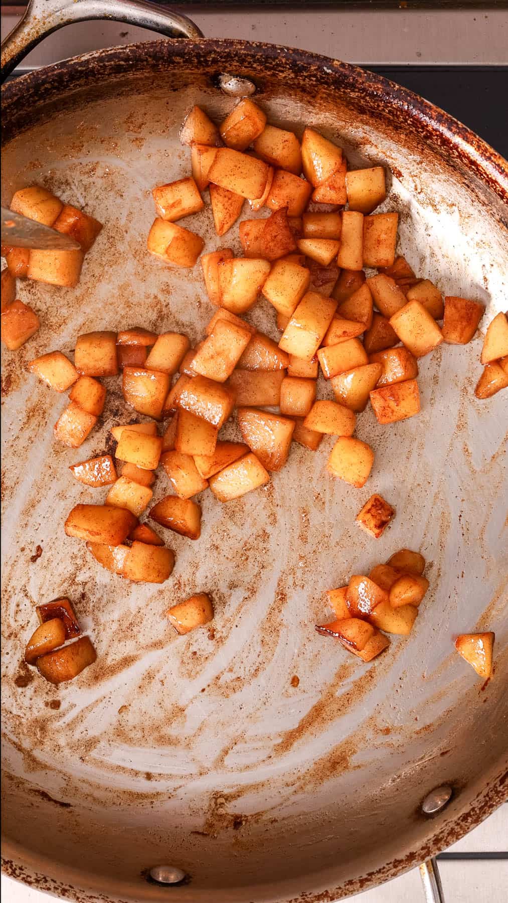 Apples caramelizing in a large skillet.