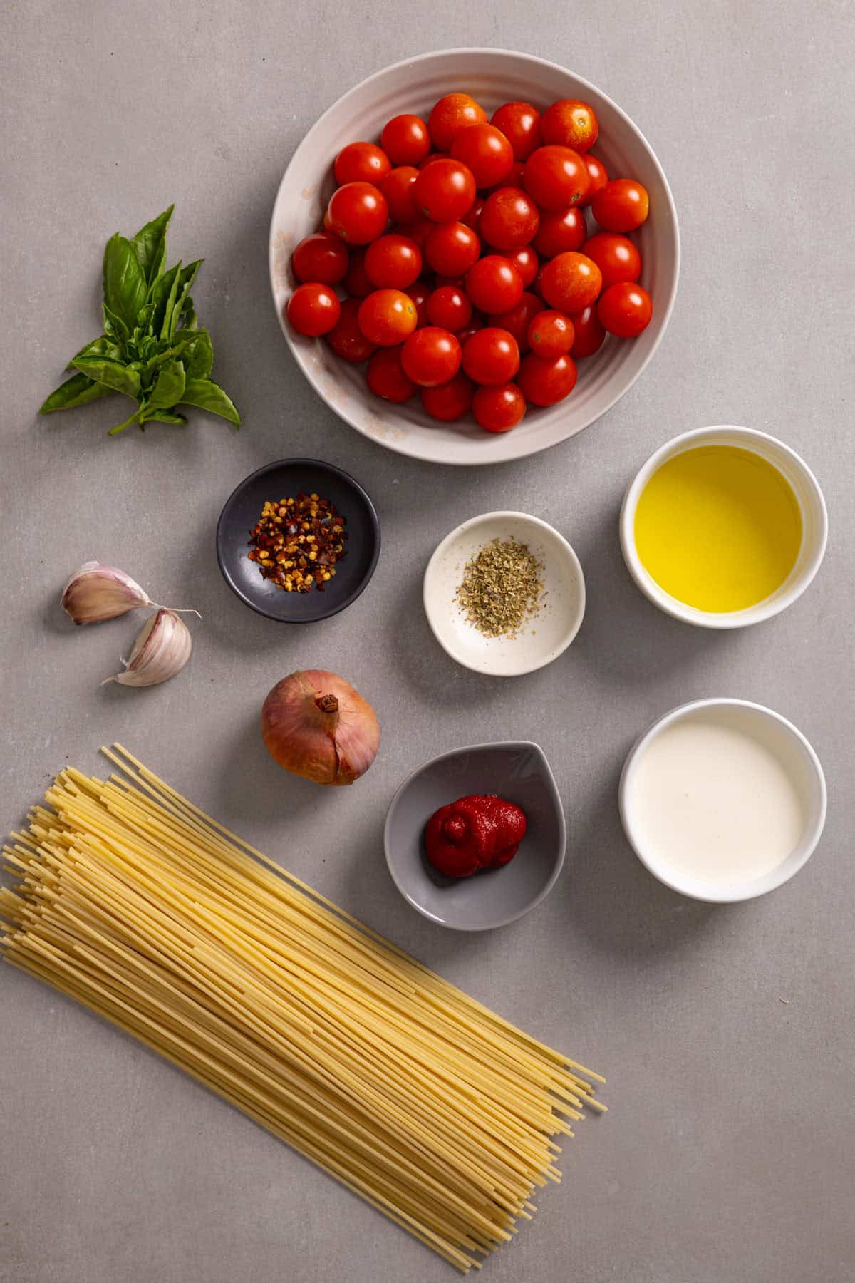 Ingredients for cherry tomato spaghetti sauce on a gray table.