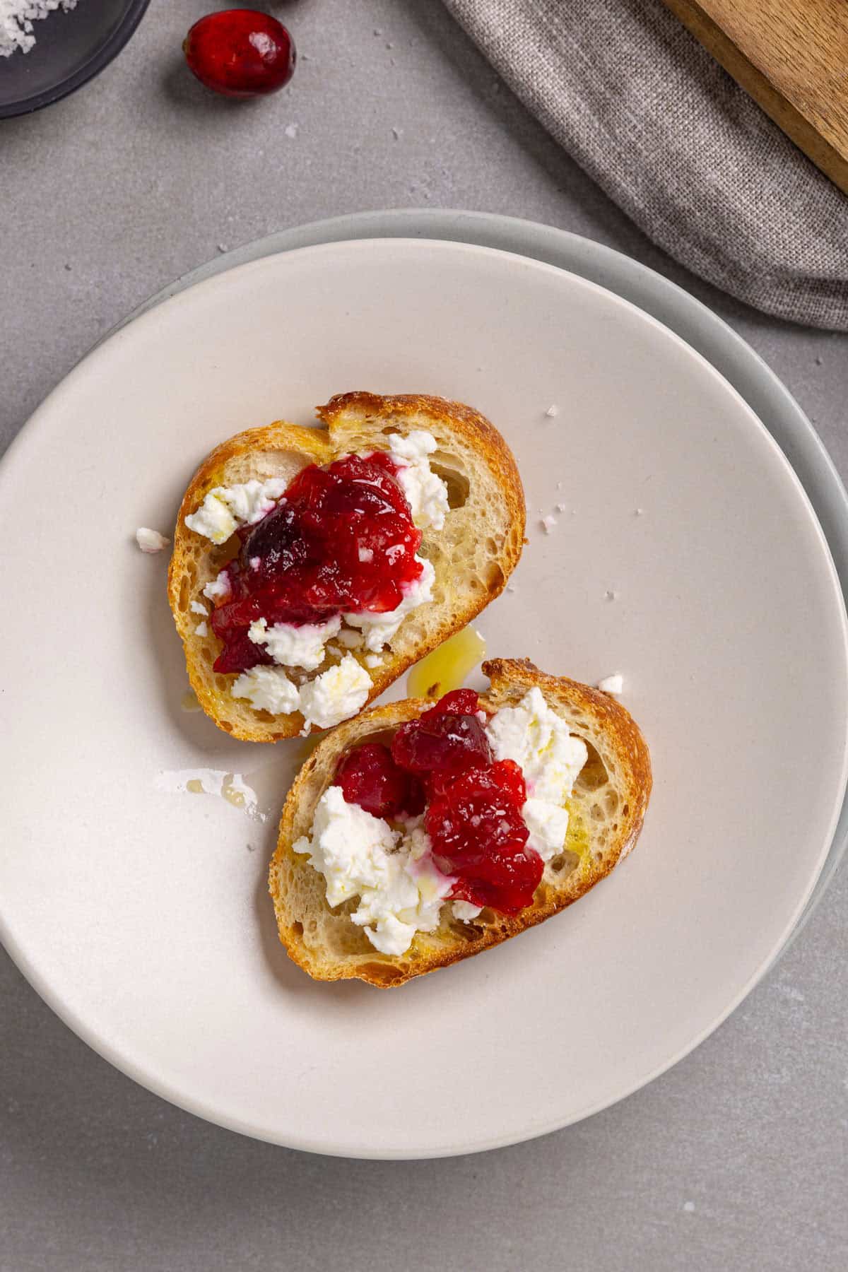 A close-up of cranberry and goat cheese crostini on a small plate.